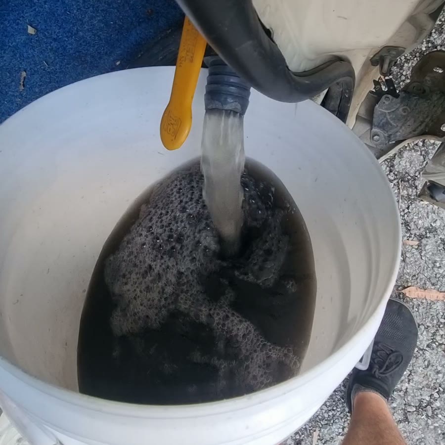 Black, dirty water draining from the carpet extraction tank into a bucket