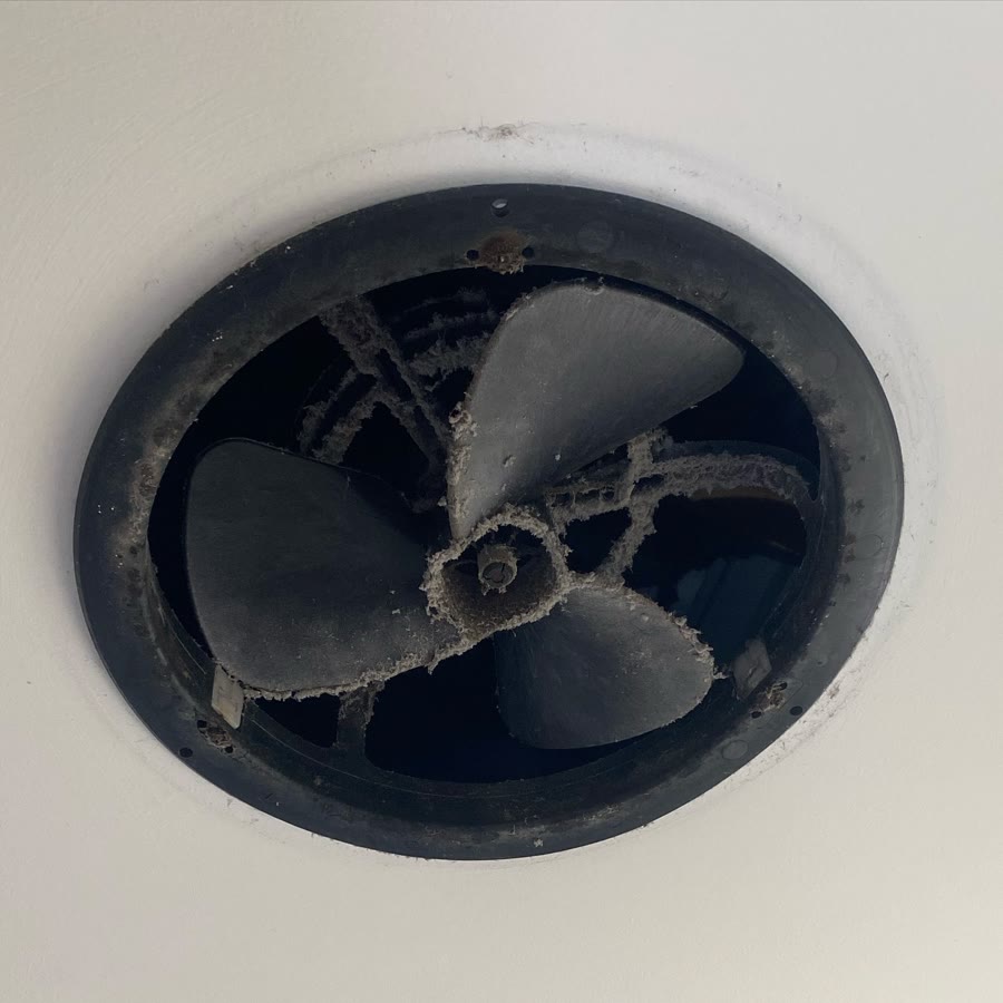 A bathroom exhaust fan coated in dust and grime before cleaning